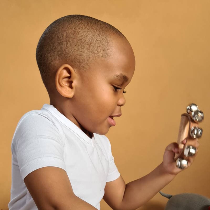 Dziecko trzymające drewniane grzechotki z metalowymi dzwoneczkami zestaw instrumentów muzycznych dla dzieci. Egmont Toys Zestaw instrumentów muzycznych