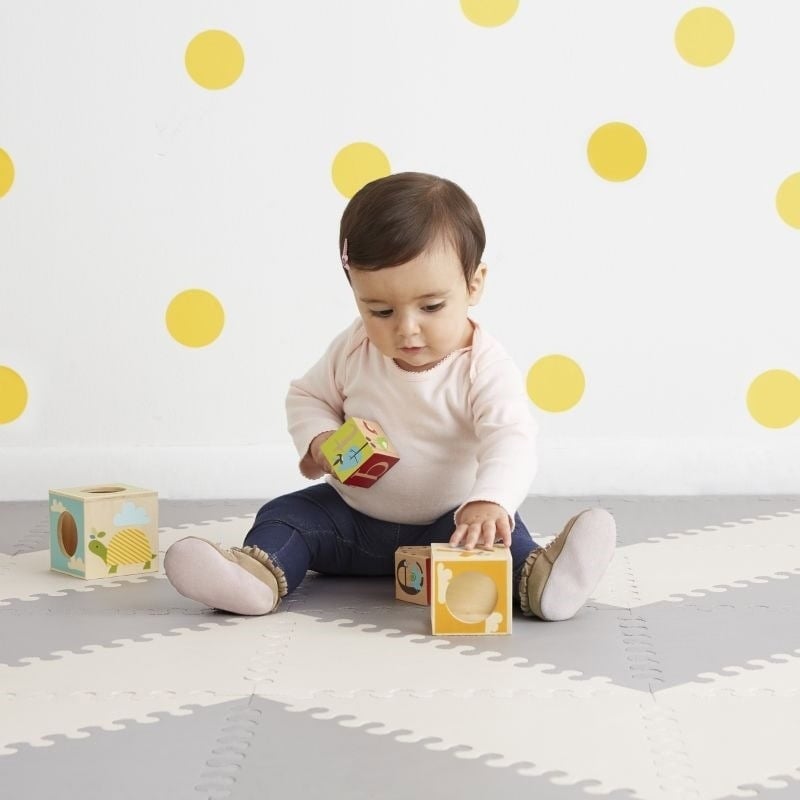 Dziecko bawiące się na szaro-kremowej piankowej macie z geometrycznym wzorem dla niemowląt. Skip Hop Mata Playspot Grey/Cream GEO
