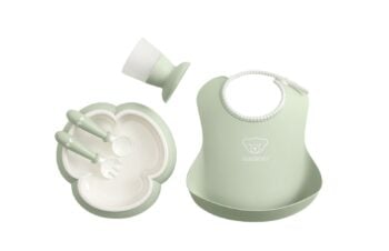 Zestaw do karmienia dla dziecka w kolorze zielonym zawierający talerz, sztućce, kubek i śliniak. BABYBJORN Zestaw obiadowy Powder Green