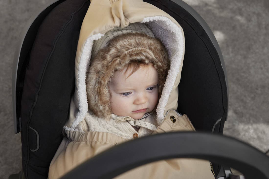 Dziecko w beżowej zimowej czapce z futerkiem dla niemowlaka w foteliku samochodowym. Elodie Details Czapka Winter Bonnet Pinstripe 1-2 lata