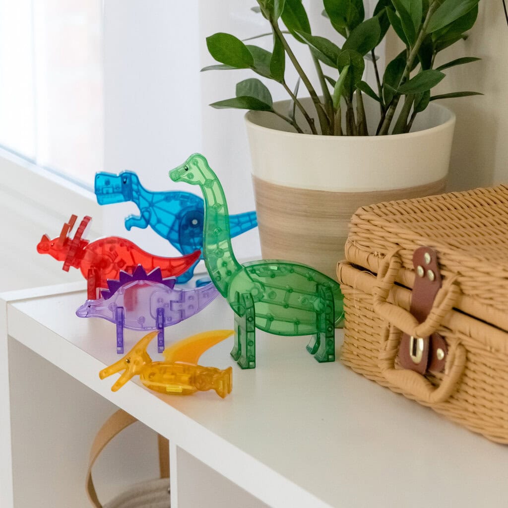 Kolorowe klocki magnetyczne w kształcie dinozaurów na białej półce dla dzieci. Magna-Tiles Klocki Magnetyczne Zestaw Dino 5 el