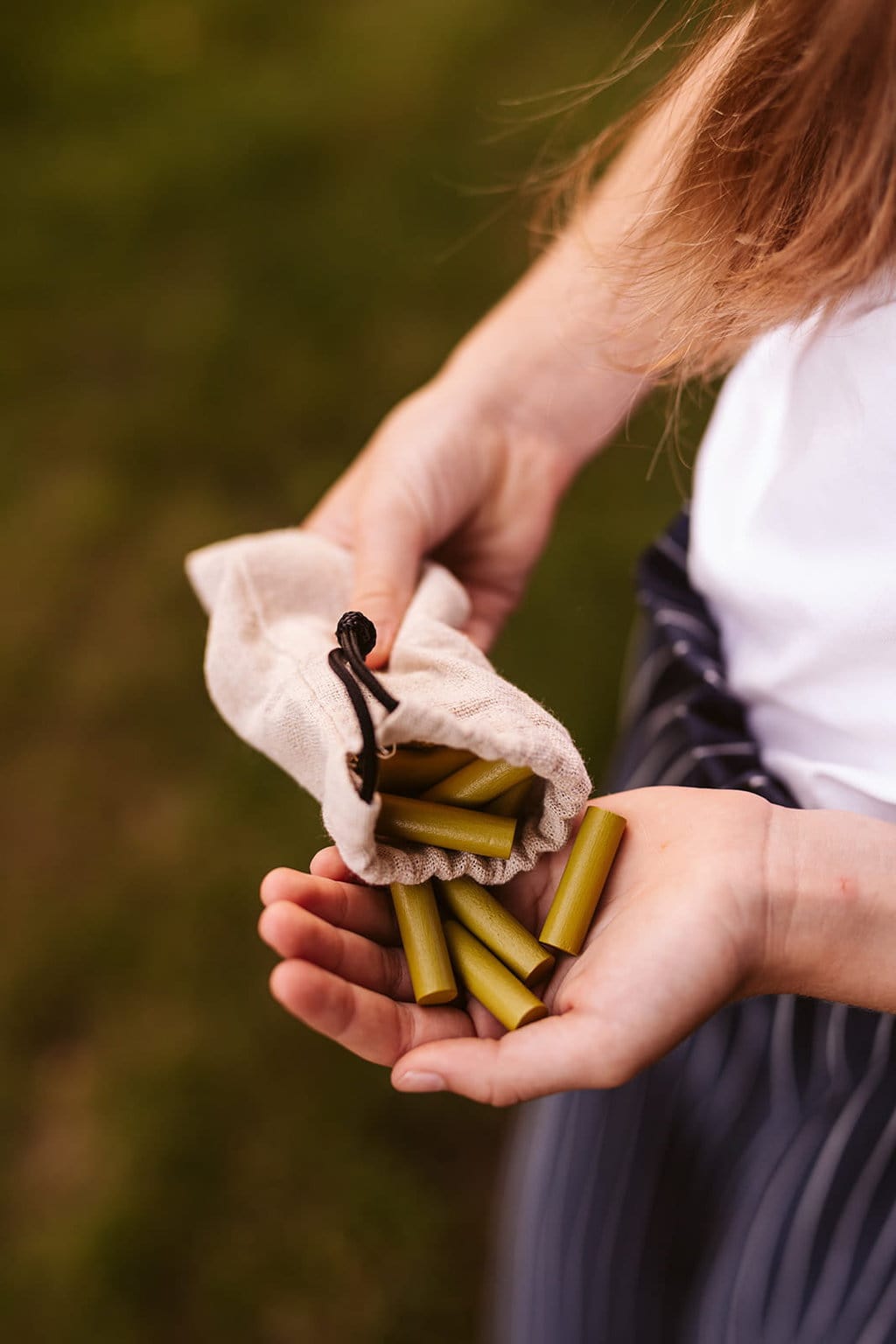 Ręce trzymające woreczek z zielonymi pałeczkami do karmienia konia na kiju dla dziecka. byAstrup Zestaw do karmienia konia na kiju Hobby Horse