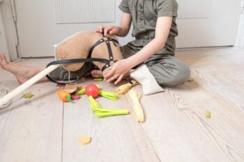 Dziecko bawiące się zestawem do karmienia konia na kiju z plastikowymi warzywami i owocami na jasnej podłodze. byAstrup Zestaw do karmienia konia na kiju Hobby Horse