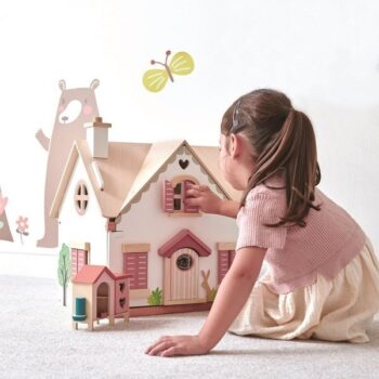 Drewniany dwupiętrowy domek dla lalek z wyposażeniem w jasnych kolorach dziewczynka bawiąca się domkiem. Tender Leaf Toys drewniany dwupiętrowy domek dla lalek z wyposażeniem 3+