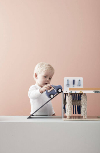 Dziecko bawiące się drewnianym centrum serwisowym 3w1 z niebieskim samochodem zabawką. Kid’s Concept Centrum serwisowe 3w1 AIDEN