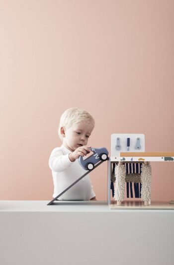 Dziecko bawiące się drewnianym centrum serwisowym 3w1 z niebieskim samochodem zabawką. Kid’s Concept Centrum serwisowe 3w1 AIDEN