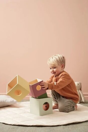 Dziecko układa drewniane kolorowe kostki do zabawy na jasnym dywanie dla niemowlaka. Kid’s Concept Drewniane kostki do układania EDVIN 1+
