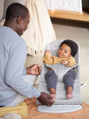 Jasnoszary leżaczek dla niemowlaka z miękkim siedziskiem i pasami bezpieczeństwa z zabawką z oczkami dla dziecka. BABYBJORN leżaczek BLISS Woven, Petal Quilt, Jasnoszary + Zabawka Googly Eyes Pastels