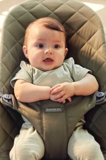 Niemowlę siedzące w ciemnozielonym pikowanym leżaczku dla dziecka. BABYBJORN Leżaczek BLISS Woven Ciemnozielony