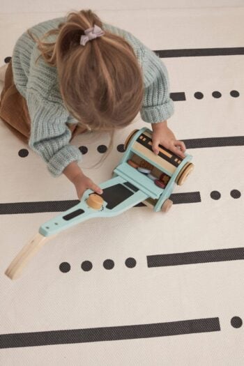 Drewniany odkurzacz do zabawy w kolorze miętowym dla dziecka na jasnym dywanie z czarnymi kropkami i liniami. Kid’s Concept Odkurzacz do zabawy KID´S HUB