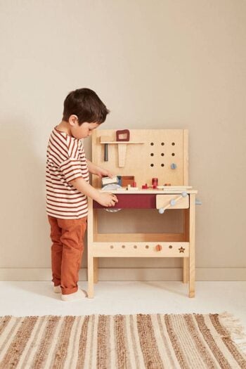 Drewniany stół z narzędziami do majsterkowania dla dziecka z akcesoriami i młotkiem na tle jasnej ściany. Kid’s Concept Stół z narzędziami KID’S HUB