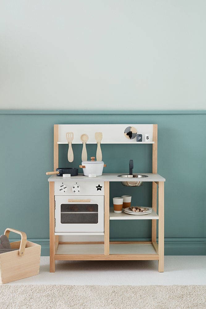 Drewniana kuchnia dla dzieci w kolorze naturalnym i białym z akcesoriami kuchennymi zawieszonymi na wieszaku. Kid’s Concept Kuchnia KID’S HUB, natural/white