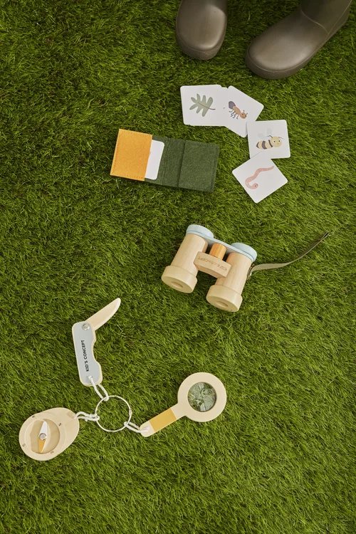 Drewniany zestaw odkrywcy dla dziecka z lornetką lupą kartami do obserwacji owadów na zielonej trawie. Kid’s Concept Zestaw odkrywcy KID’S HUB