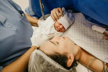 Noworodek ułożony na piersi mamy w szpitalu po porodzie kangurowanie dziecka ciążą