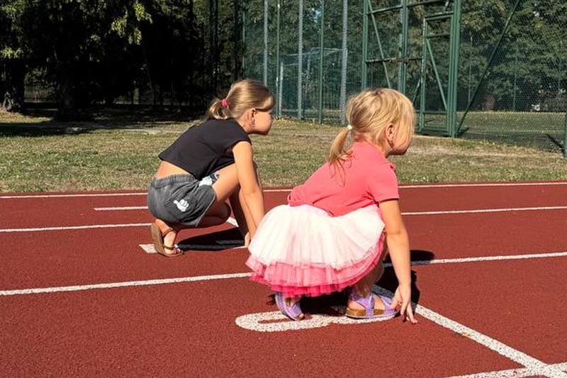 Dwie dziewczynki na torze lekkoatletycznym przygotowujące się do startu w biegu