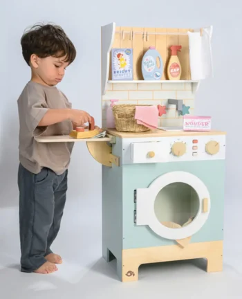 Drewniana zabawkowa pralnia z akcesoriami w pastelowych kolorach chłopiec bawi się przy pralce dla dzieci. Tender Leaf Toys Drewniana pralnia z akcesoriami