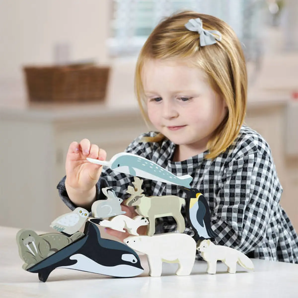 Drewniane figurki zwierząt polarnych w różnych kolorach z dzieckiem bawiącym się przy stole. Tender Leaf Toys Drewniane figurki do zabawy zwierzęta polarne