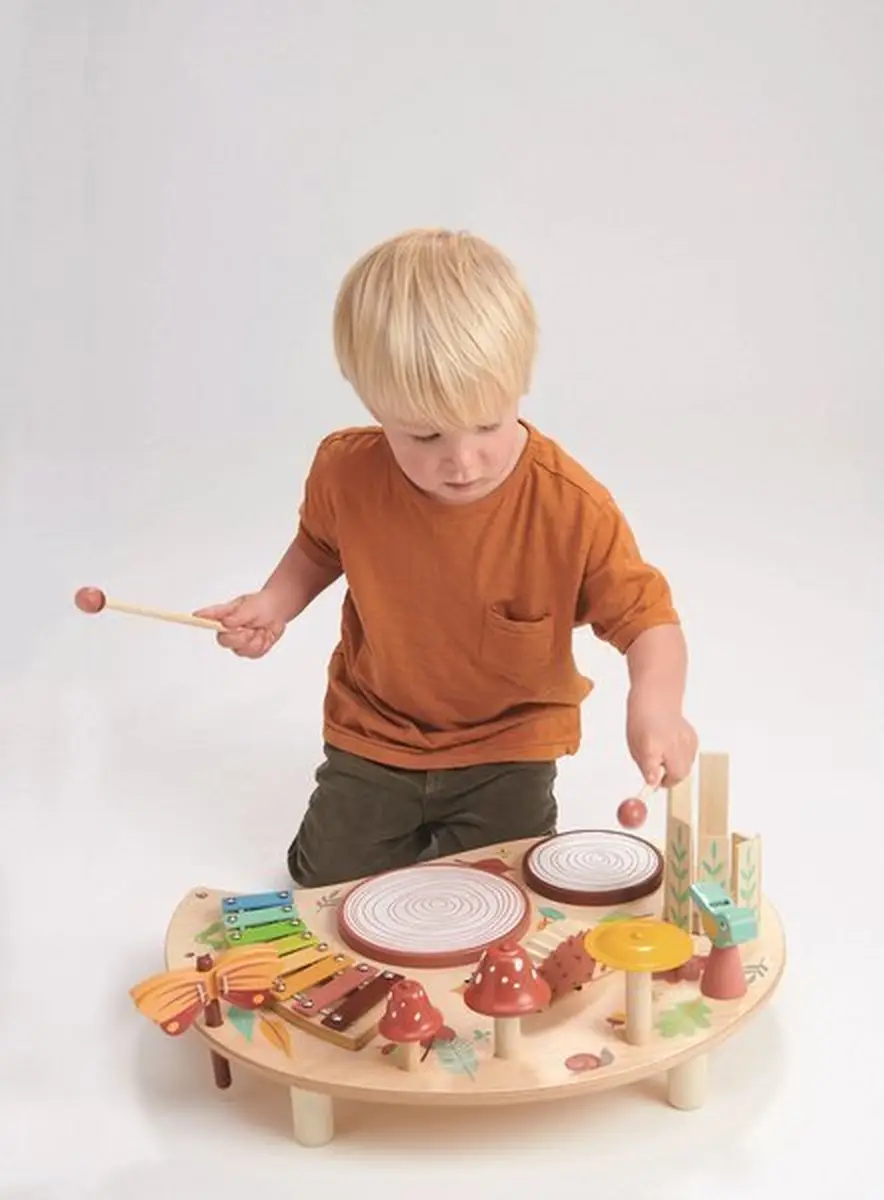 Chłopiec bawiący się drewnianym stolikiem muzycznym z kolorowymi instrumentami dla dzieci. Tender Leaf Toys Drewniany stolik muzyczny