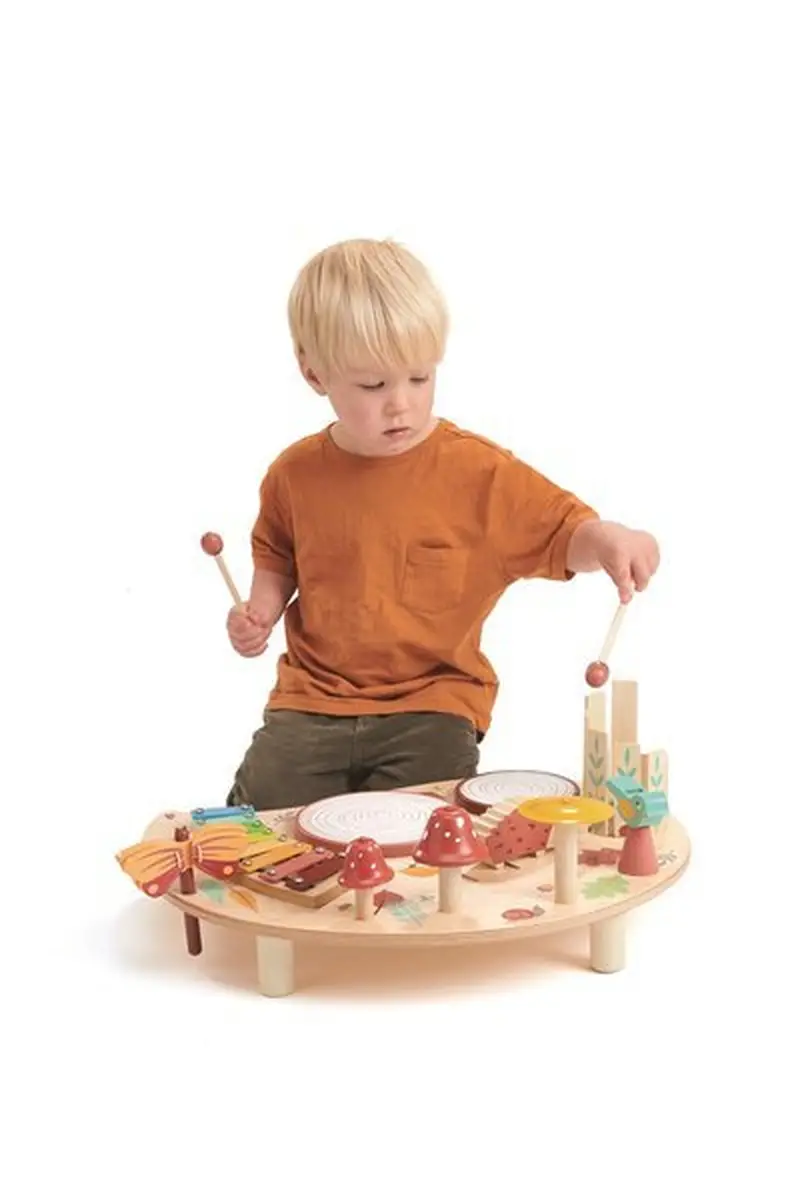 Dziecko grające na drewnianym stoliku muzycznym z różnymi instrumentami perkusyjnymi i dzwonkami. Tender Leaf Toys Drewniany stolik muzyczny