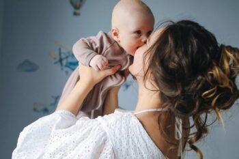 Kobieta trzymająca na rękach niemowlę w jasnym pokoju
