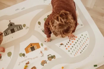 Dziecko bawiące się na dwustronnej piankowej macie edukacyjnej z motywem farmy w jasnych kolorach dla niemowlaka i dziecka. Play&Go Dwustronna Mata Piankowa EEVAA 3w1 Farm