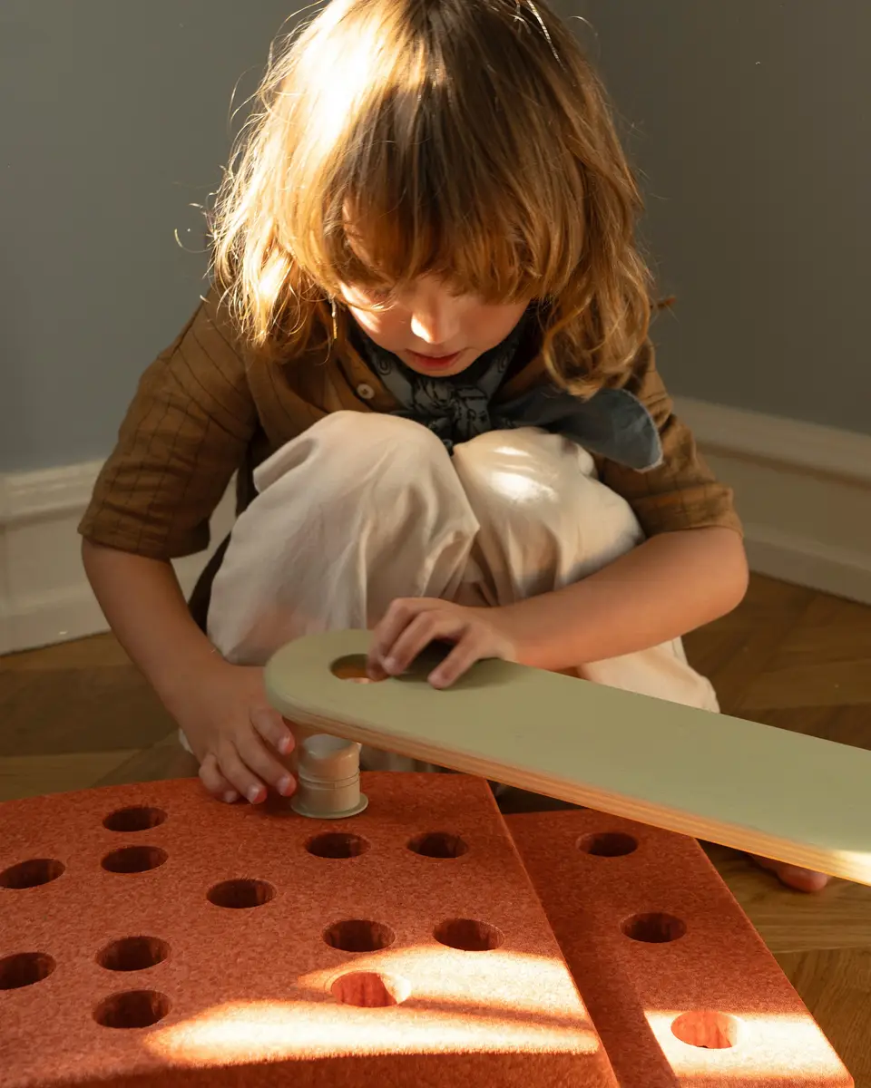 Dziecko bawiące się klockami piankowymi w kolorze spalona pomarańcza i przygaszona zieleń dla dzieci. MODU Beams 2 szt Burnt Orange / Dusty Green
