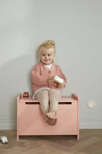 Dziewczynka bawiąca się trzema drewnianymi samochodzikami policyjnymi siedząca na różowej skrzynce do przechowywania zabawek. Kid’s Concept Zestaw samochodzików (3szt) AIDEN