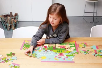 Dziewczynka układająca kolorowe puzzle z motywem księżniczki na stole 60 elementów dla dziecka. Scratch Puzzle Księżniczka 60szt