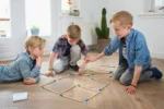 Trzy chłopcy bawiący się drewnianymi zapałkami do łamigłówek logicznych na podłodze w jasnym pokoju. BS Toys Łamigłówki Logiczne Zapałki