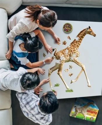Dzieci układają puzzle tradycyjne z konturem żyrafy na białym stole 100 elementów. Madd Capp Puzzle konturowe I AM LIL’ Żyrafa 100 elem