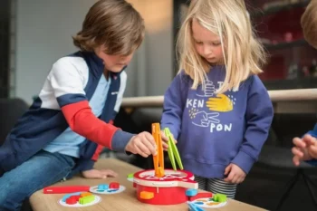 Dzieci grające w zręcznościową grę łowimy warzywa z kolorowymi elementami do łowienia. BS Toys Gra Zręcznościowa Łowimy Warzywa