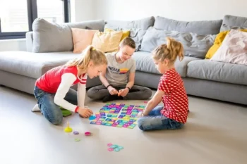 Trójka dzieci grająca w kolorową grę planszową na podłodze w salonie gra logiczna i matematyczna dla dzieci. BS Toys Gra logiczna i matematyczna dla dzieci Modny Krokodyl