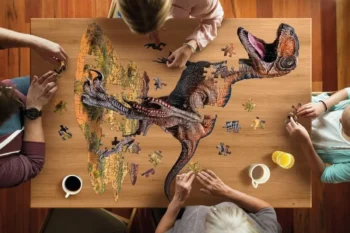 Układana układanka konturowa dinozaur raptor 100 elementów na drewnianym stole z udziałem kilku osób. Madd Capp Puzzle konturowe I AM RAPTOR 100 elem