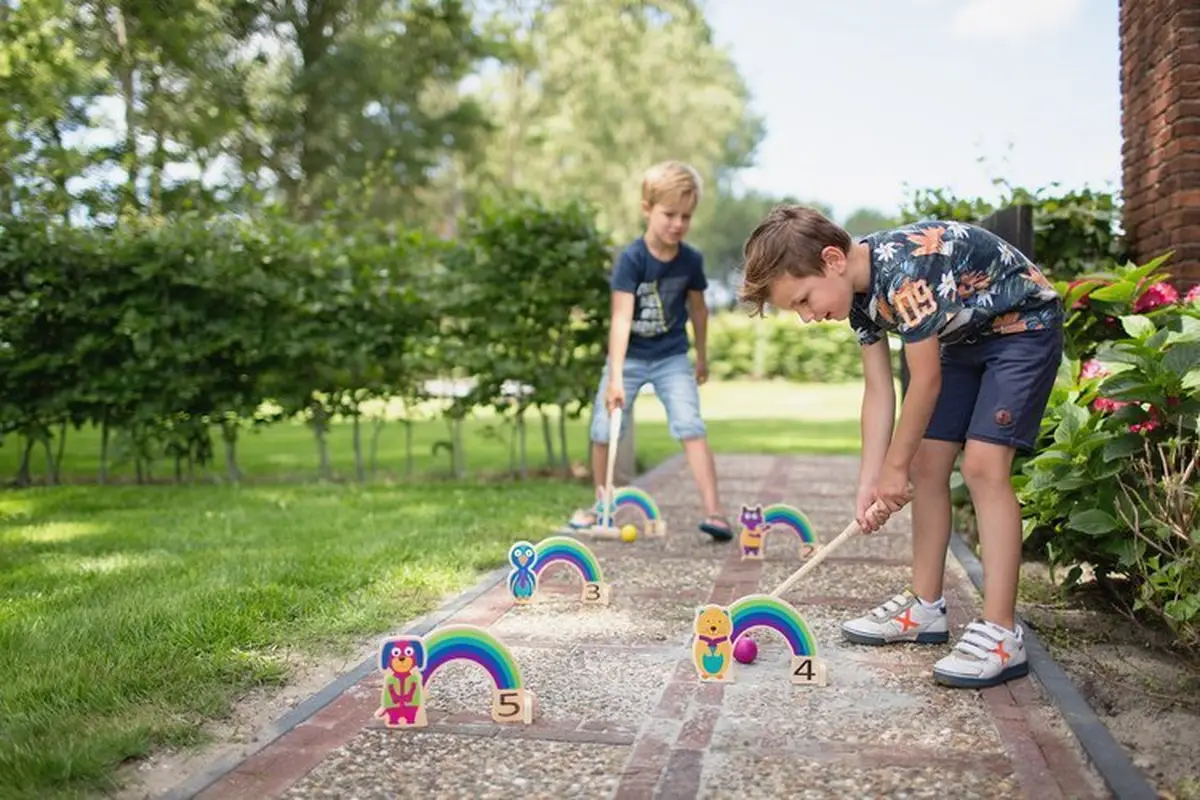 Drewniany zestaw do gry w krykieta dla dzieci z kolorowymi tęczami i liczbami na trawie i chodniku. BS Toys Drewniany krykiet dla dzieci zestaw Tęcza