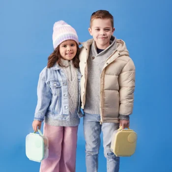 Dwoje dzieci trzymających mini śniadaniówki w kolorze miętowym i żółtym na niebieskim tle. b.box Mini Lunchbox Spearmint