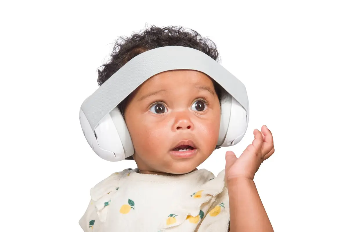 Niemowlę w białych słuchawkach ochronnych na uszy dla dzieci 0-3 lat. Dooky Słuchawki ochronne Baby Earmuff white 0-3 l