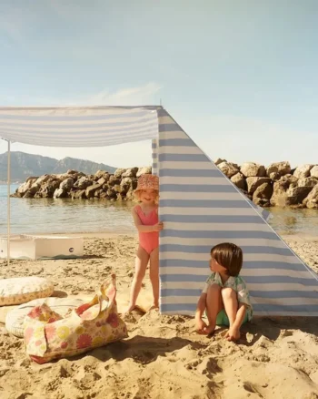 Niebiesko-biały namiot plażowy w paski dla dzieci na piasku nad morzem z dwójką dzieci obok. Kid’s Concept Namiot plażowy blue