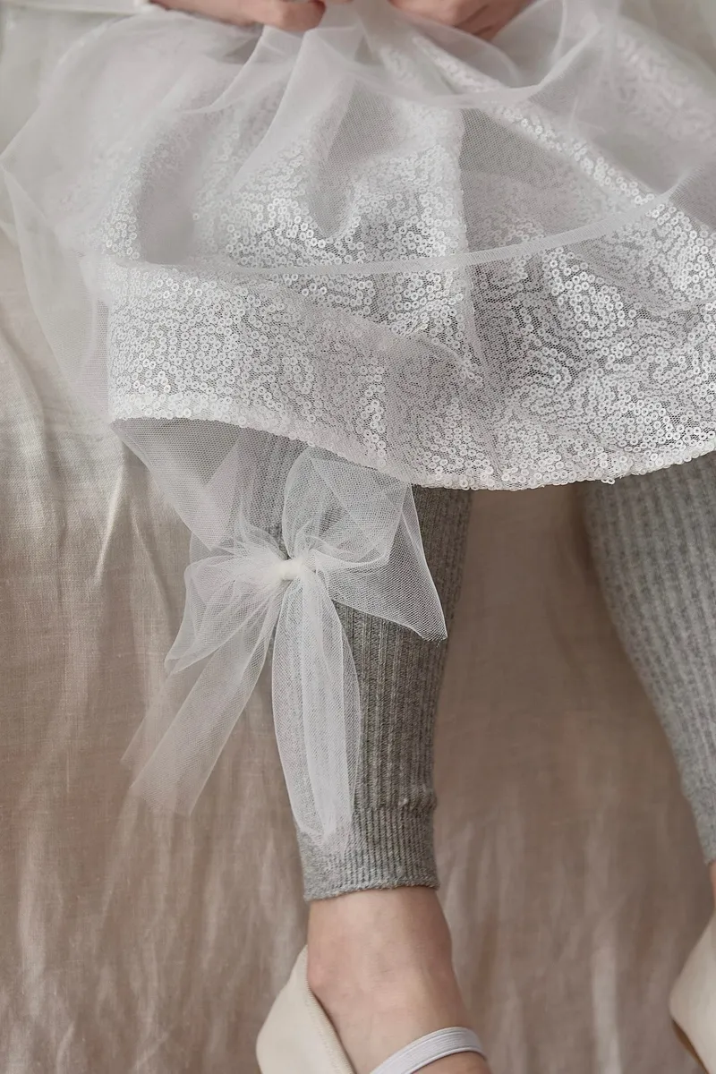 Szare legginsy dla dziecka z tiulową kokardą przy kostce pod białą tiulową sukienką. Fig&Pear Legginsy z tiulową kokardą Sandy Grey