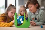 Dzieci grające w zieloną drewnianą grę zręcznościową z krokodylem i kolorowymi krążkami na stole. BS Toys Gra zręcznościowa Głodny krokodyl Croco