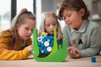Dzieci grające w zieloną drewnianą grę zręcznościową z krokodylem i kolorowymi krążkami na stole. BS Toys Gra zręcznościowa Głodny krokodyl Croco
