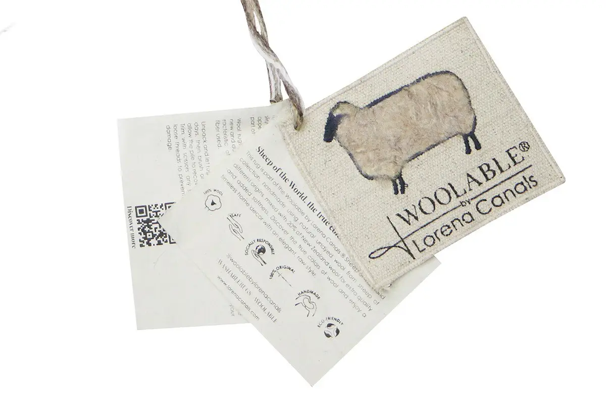 Zawieszka z ilustracją owcy i informacjami o produkcie z papieru. Lorena Canals Dywan wełniany Woolly Beige 75x110cm