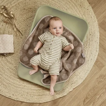 Mata do przewijania na komodę w kolorze oliwkowej zieleni z miękkim brązowym kocykiem w kropki dla niemowlaka. Leander mata do przewijania MATTY olive green