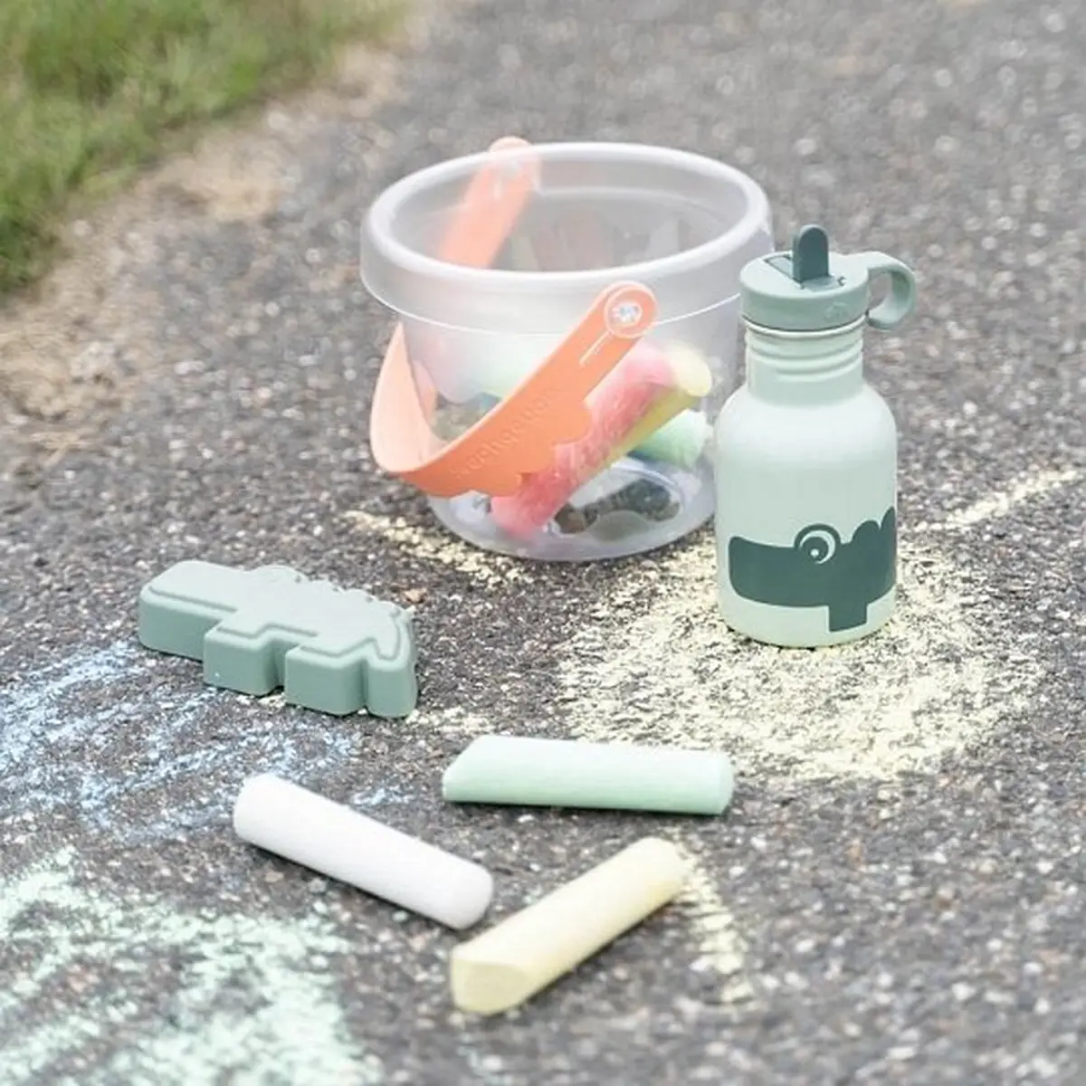 Metalowa butelka ze słomką dla dziecka w kolorze pudrowym, pojemność 350 ml, obok kredy i plastikowego pojemnika na zabawki. Done by Deer Butelka Metalowa ze Słomką dla Dziecka Ozzo Powder 350 ml