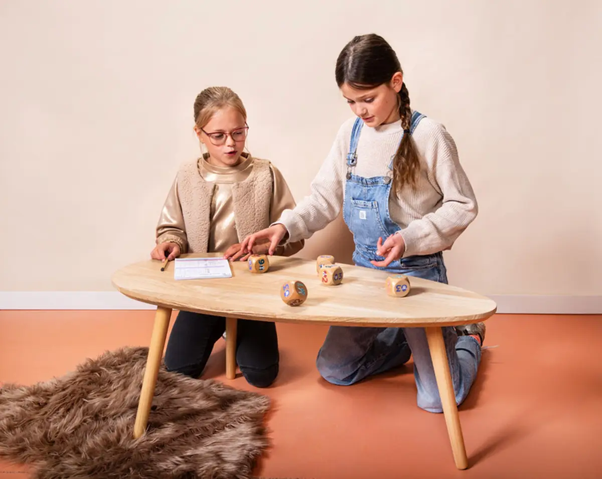Dwie dziewczynki grające przy drewnianym stole w grę zręcznościową z drewnianymi kośćmi na spostrzegawczość. BS Toys drewniana gra na spostrzegawczość Gra w kości