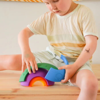 Dziecko bawiące się kolorową sensoryczną tęczą z pięciu elementów z tworzywa. Jellystone Designs Jellystone Tęcza sensoryczna Over the rainbow Bright 5el