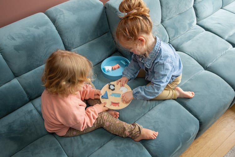 Dwoje dzieci bawiących się drewnianym sorterem zwierząt arktyki na niebieskiej sofie. BS Toys Drewniany sorter Zwierzęta Arktyki