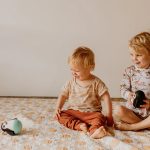 Dzieci bawiące się miękką wańką wstańką pingwin niebieski na podłodze. Jellystone Designs Jellystone Wańka wstańka Pingwin soft BLUE