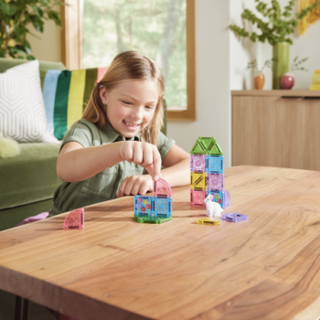 Dziewczynka bawiąca się kolorowymi przezroczystymi klockami magnetycznymi na drewnianym stole dla dziecka. Magna-Tiles Klocki Magnetyczne microMAGS Spring Garden Travel 24el