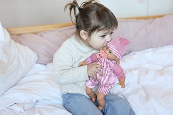 Dziewczynka bawiąca się lalką bobasem w różowym ubranku z czapeczką dla dziecka. Micki Duża lalka Alice 30cm bobas +smoczek zabawka dla dzieci Lillan & Friends