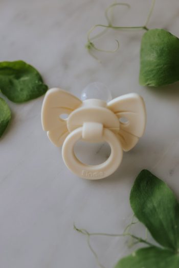 Smoczek silikonowy dla niemowlaka w kolorze kremowym z ozdobą w kształcie kokardki. Elodie Details smoczek silikonowy Binky Bow 0-6m oat white